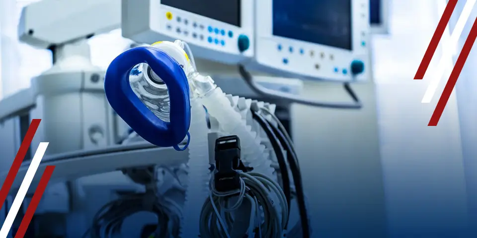 A ventilator mask attached to a breathing machine sits in a medical setting.